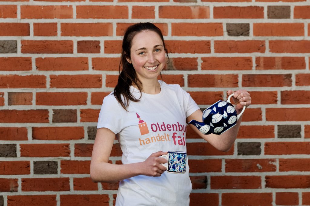 Mädchen in T-Shirt mit dem Logo von Oldenburg handelt fair und Teekanne und -tasse in den Händen. Foto: © J. Bädeker