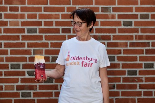 Frau in T-Shirt mit dem Logo von Oldenburg handelt fair und Oldenburg Kaffee in den Händen. Foto: © J. Bädeker
