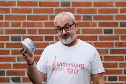 Mann in T-Shirt mit dem Logo von Oldenburg handelt fair und nachhaltiger Dose in den Händen. Foto: © J. Bädeker