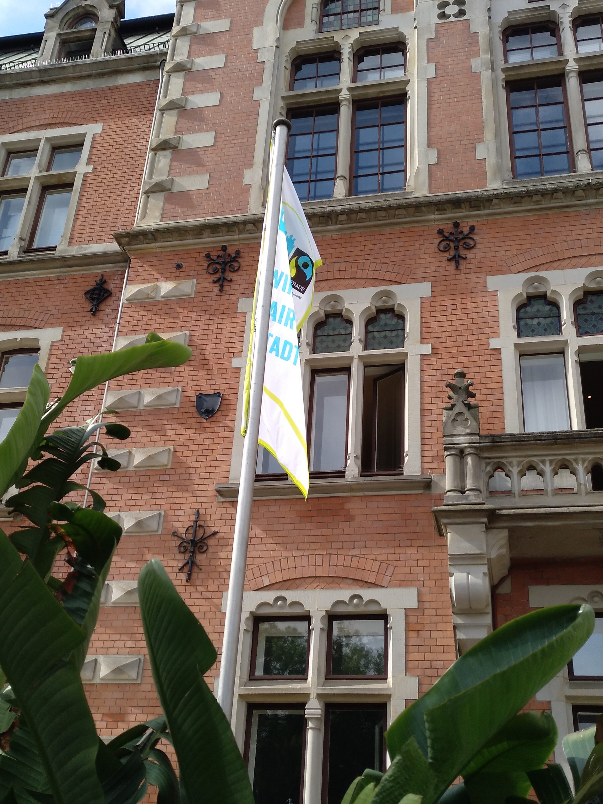 Die Flagge zur Rezertifizierung der Stadt Oldenburg als Fairtrade Stadt hängt im Zeitraum der bundesweiten Fairen Woche vor dem Rathaus.