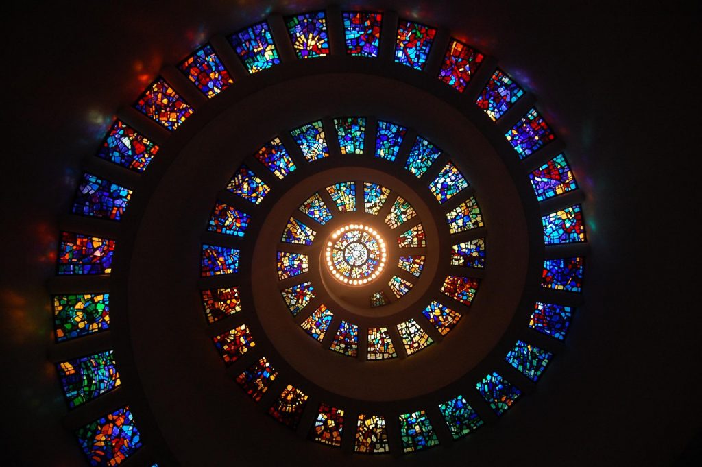 Auf dem Bild sind Buntglasfenster in einer Spirale zu sehen. Foto: © Pixabay