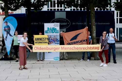 Es sind Menschen, die verschiedene Banner halten, zu sehen, die sich alle am Menschenrechtstag beteiligen. Foto: © J. Bädeker