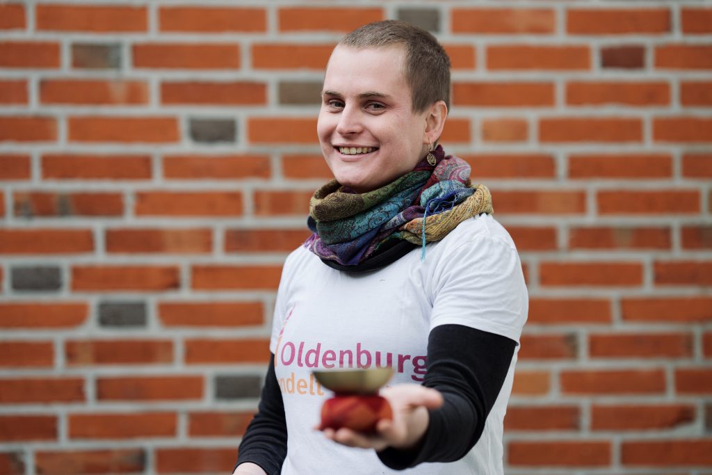 Eine Frau, Pia Schäfer, steht vor einer Backsteinwand mit einer Klangschale in der Hand. Foto: © J. Bädeker